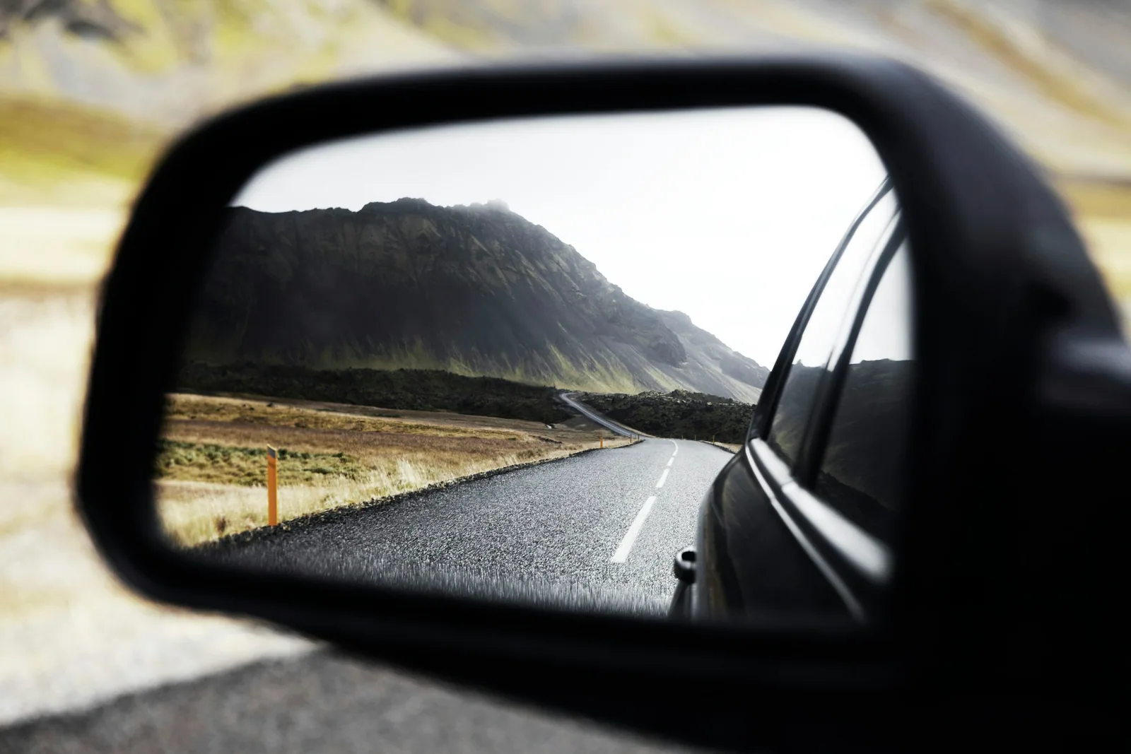 Side mirror view of an open road, used to teach defensive driving
